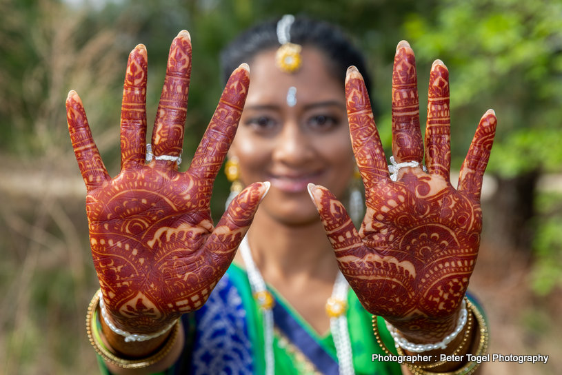 Photo of sisters and friends of the bride pose as the bride gets her  mehendi done