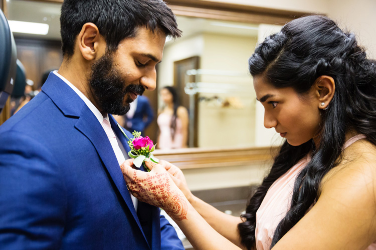 Indian Groom's Sister Ties Flower on Groom's Suit