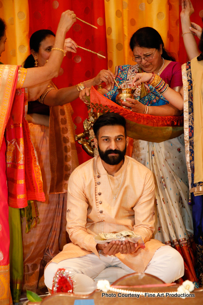 Indian wedding ritual of painting the groom with yellow turmeric paste