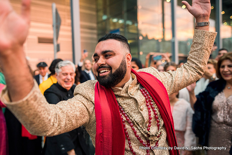 Indian groom dancing with wedding guest in Baraat