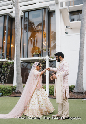Newlyweds posing for a candid photo during their wedding day, surrounded by lush greenery and palm trees.