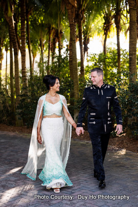 Outdoor portrait of the wedding couple at sunset with lush greenery and sea in the background