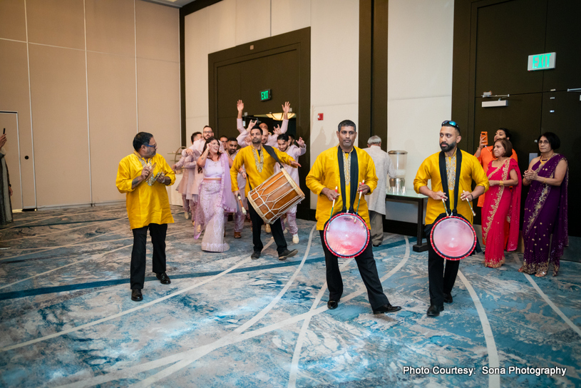 Traditional Indian wedding celebration with drummers and guests in festive attire enjoying music and dance indoors. Traditional Indian wedding celebration with drummers and guests in festive attire enjoying music and dance indoors.