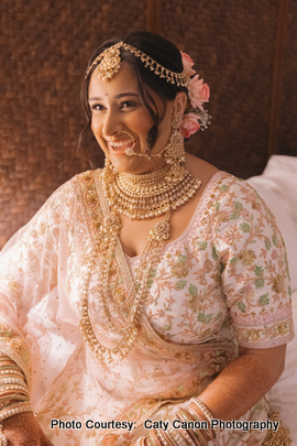 The bride posing gracefully with henna-decorated hands and floral decorations in her hair