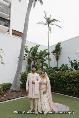 Newlyweds posing for a candid photo during their wedding day, surrounded by lush greenery and palm trees.