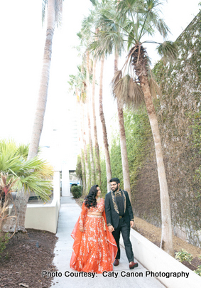 The bride and groom smiling and dressed in elegant wedding attire during their outdoor photoshoot.
