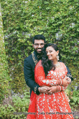 Ami wearing a red lehenga and Vinny in a black and gold sherwani at the outdoor photoshoot