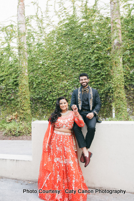 The bride and groom smiling and dressed in elegant wedding attire during their outdoor photoshoot. 