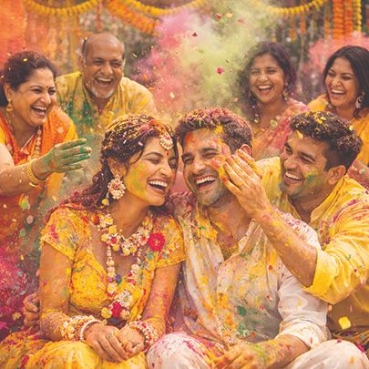 Indian groom and bride laughing during the haldi and pithi ceremony with family and friends