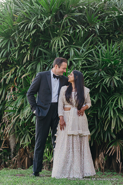 Sujata and Mark standing together near greenery during their wedding photoshoot