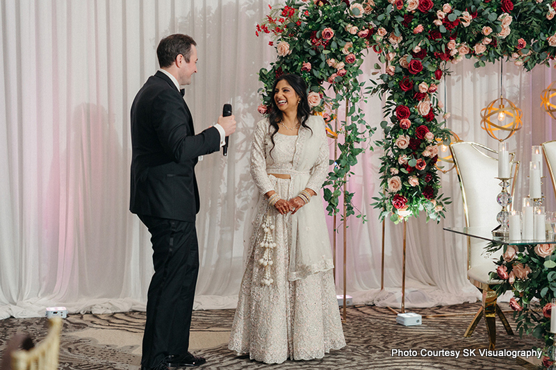 Sujata and Mark exchanging vows during their wedding ceremony under floral arch Sujata and Mark exchanging vows during their wedding ceremony under floral arch